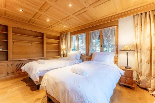 two beds in a bedroom with wooden ceilings and windows at Chalet Eclipse, The Hidden Wonder in Hornkessel