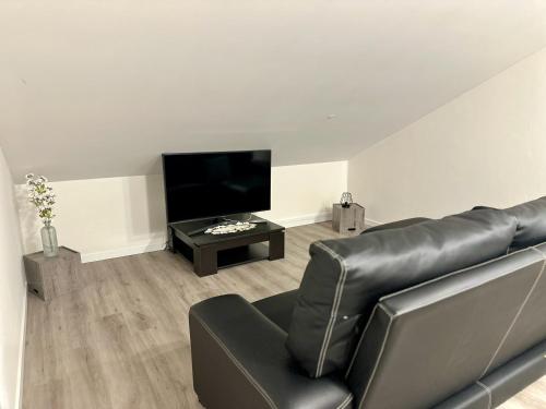 a living room with a black leather couch and a flat screen tv at Cantinho dos Sonhos in Santa Cruz