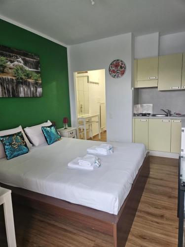 a bedroom with a large white bed with a green wall at Tropical Lugano in Lugano