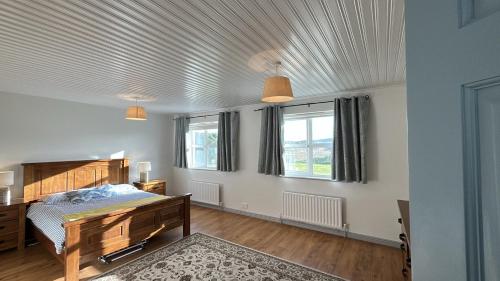 a bedroom with a bed and two windows at Doonloughan View, Ballyconneely in Ballyconneely