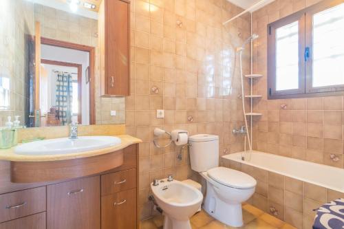 a bathroom with a toilet and a sink and a tub at La Encina in Port d'Alcudia
