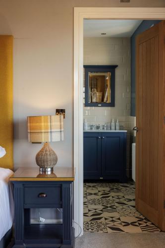 a bedroom with a bed and a table with a lamp at The Sunningdale in Bamburgh