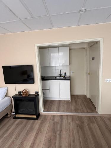 a living room with a couch and a tv and a kitchen at Studio Huzur in Deventer
