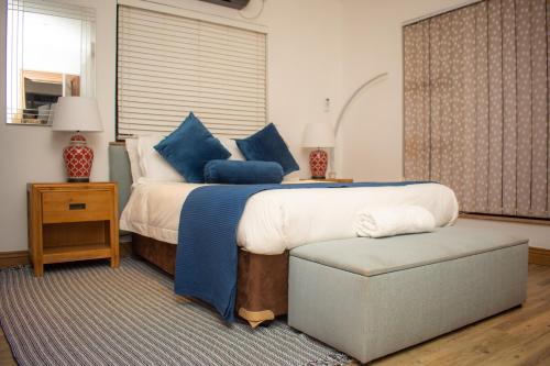 a bedroom with a large bed with blue pillows at Nkandla Resort in Bulawayo