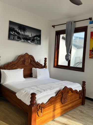 a bedroom with a wooden bed and a window at Jamaica House in Nungwi