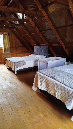 two beds in a room with wooden floors at Chalé Azaléia in Campo Alegre