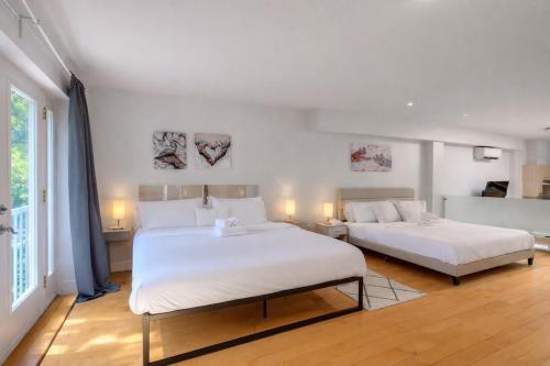 two beds in a room with white walls at Loft The White Pearl Plateau-Mont-Royal 3 Beds in Montréal