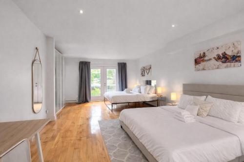 a white room with two beds and a table at Loft The White Pearl Plateau-Mont-Royal 3 Beds in Montréal