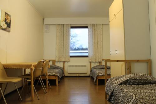 a room with two beds and a table and a window at Guesthouse - Kuin Kotonaan in Kotka