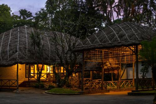 two houses with thatched roofs in the night at Spice Village Thekkady - A CGH Earth Experience in Thekkady