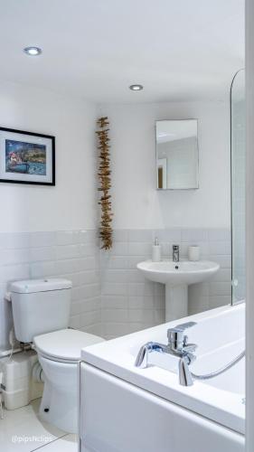 a white bathroom with a toilet and a sink at Superb Cintra Beachside Apartments in Llandudno