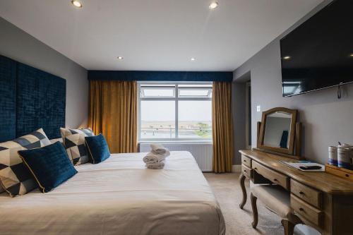 a bedroom with a large bed with a dresser and a mirror at The Sunningdale in Bamburgh