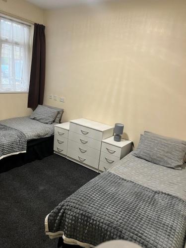 a bedroom with two beds and a dresser and a window at Rugby House in Birmingham
