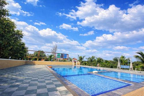 a large swimming pool with a blue sky with clouds at The Crystal Woods Resort in Mendarda