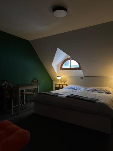 a bedroom with a bed with a window and a table at Hostel John Galt in Brno