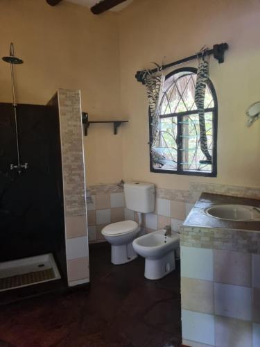a bathroom with a toilet and a sink and a window at Sofia House - Beach Paradise with Kite, Dive and more in Watamu