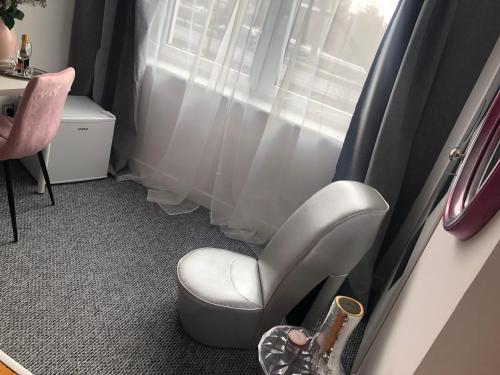 a white chair in a room with a window at Gold Angel in Poznań