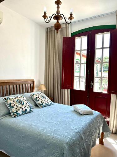 a bedroom with a bed with blue sheets and a window at Solar de Amelia in Tiradentes
