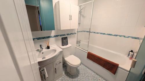 a bathroom with a toilet and a sink and a shower at 70's Inspired 1 Bed flat in Knebworth