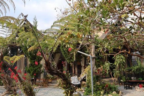 a garden with trees and plants in front of a building at Trạm Chill Homestay in Khu Chi Lăng