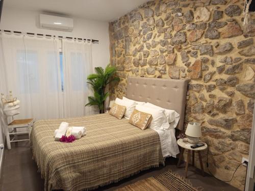 a bedroom with a bed with a stone wall at Ananda Beach Rooms - Castillo de Peñiscola in Peniscola