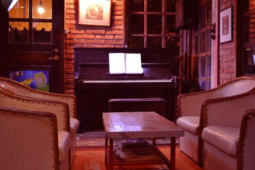 a piano in a room with a table and chairs at BRICKHOUSE Ayutthaya Guesthouse EST 1986 in Phra Nakhon Si Ayutthaya