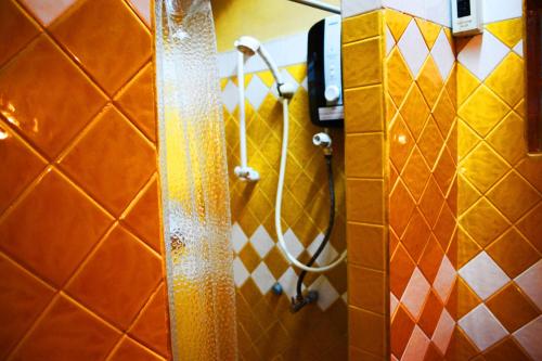 y baño con ducha y azulejos de color naranja y blanco. en BRICKHOUSE Ayutthaya Guesthouse EST 1986, en Phra Nakhon Si Ayutthaya