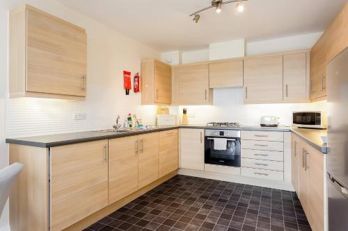 a kitchen with wooden cabinets and a black counter top at Coxswain's Cabin - Moments from Hamworthy Beach and Park in Poole