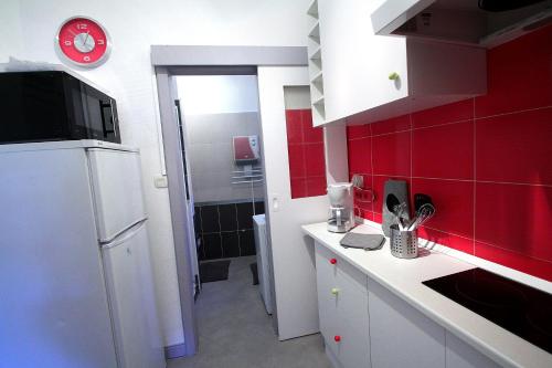 een keuken met rode tegels en een witte koelkast bij Riquewihr in Riquewihr