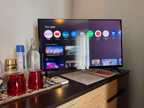 a television on a desk with a bottle and glasses at Airport Accommodation Bedroom with your own private Bathroom Self Check In and Self Check Out Air-condition Included in Mqabba