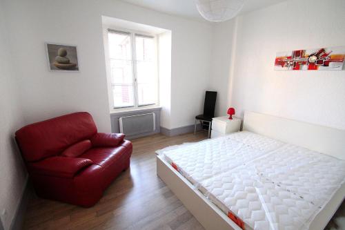 a bedroom with a white bed and a red chair at Riquewihr in Riquewihr