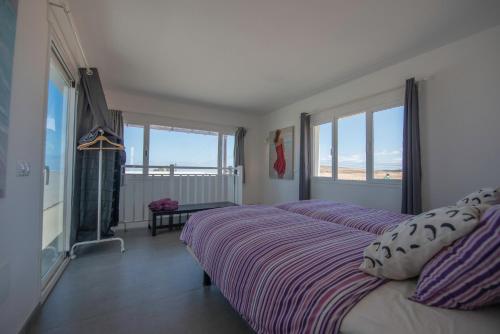 a bedroom with a bed with purple sheets and windows at Lanzarotearena in Tinajo