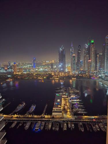 a city skyline at night with boats in the water at Luxury Penthouse Retreat - Private Beach, Breathtaking Palm and Marina Views in Dubai