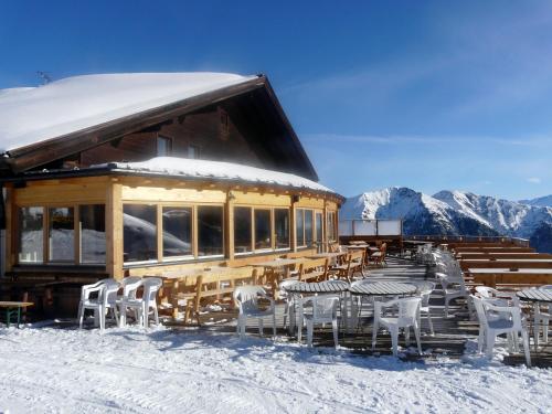 a building with tables and chairs in the snow at Berggasthaus Edelweisshütte Ladurns in Fleres