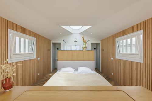 a large bed in a room with two windows at Lua Beach House in Zandvoort