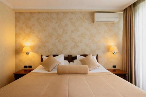 a bedroom with a large bed with two tables and two lamps at Grand Hotel & Spa Tirana in Tirana