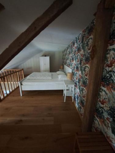 a bedroom with a white bed and a wall at À la Grange d'en Haut in Bras-Haut