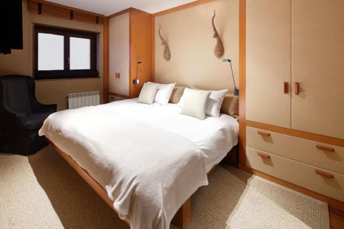 1 dormitorio con 1 cama blanca grande y 1 silla en Pleta de Nheu 2 by FeelFree Rentals, en Baqueira Beret