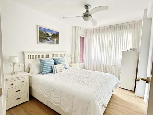 a white bedroom with a large bed with blue pillows at MUNDAKA Centre 2 in Mundaka