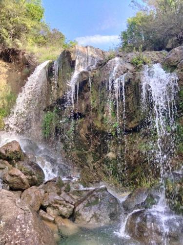 a waterfall on the side of a mountain with rocks at Hillside Haven in Sutorina