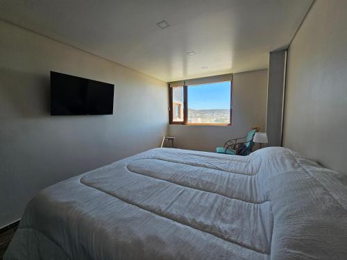 a bedroom with a large bed and a flat screen tv at Apart Sei - Rada Tilly - in Rada Tilly