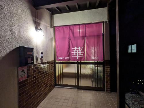 an entrance to a building with a pink sign on the door at happy stay HANA in Sakaide