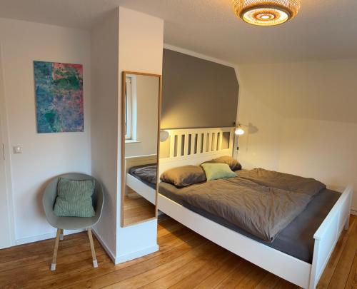 a bedroom with a bed and a mirror and a chair at Schwalbennest Flensburger Förde in Westerholz