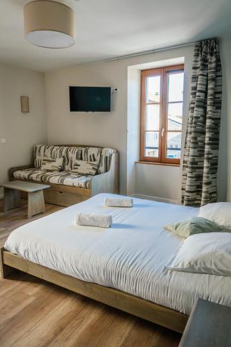 a bedroom with two beds and a couch at Hôtel Bistrot Les Tanins in Saint-Antoine