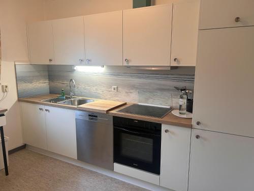 a kitchen with white cabinets and a sink and a refrigerator at Küstenhuus in Utersum