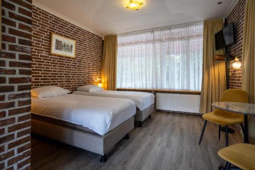 a hotel room with two beds and a brick wall at Buitengoed de Panoven in Zevenaar