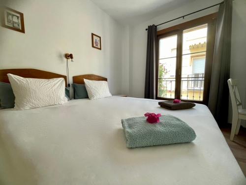a bedroom with a white bed with a towel and a window at Boutique Hostal Lorca in Nerja