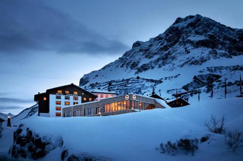 a building in the snow in front of a mountain at Hotel Zürserhof in Zürs am Arlberg