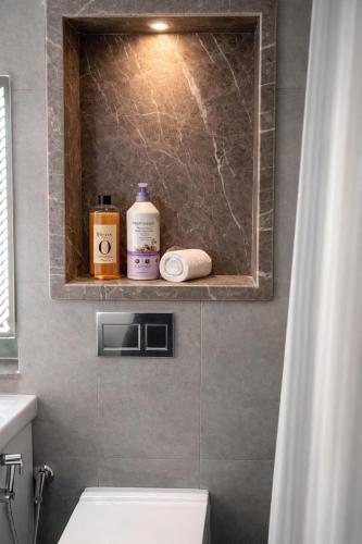 a bathroom with a toilet and a shelf with soap and toiletries at Yamunaviewnest in Noida