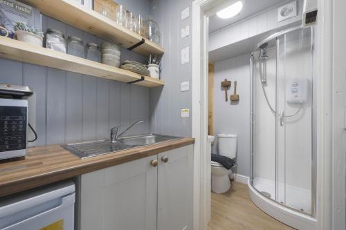 a small kitchen with a sink and a refrigerator at The Grain store in Cirencester
